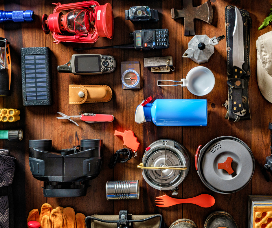A variety of camping equipment is laid our on a wooden table in an organized fashion.